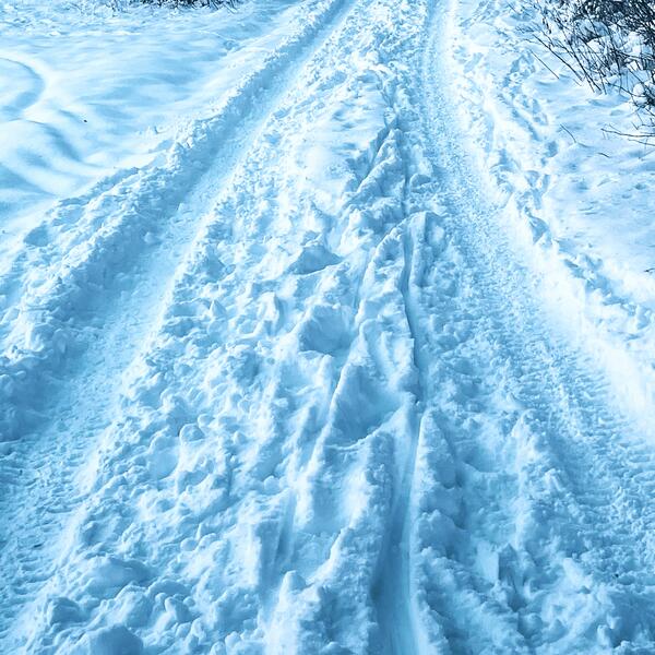 Festgefahrener Schnee mit Reifenspuren auf einem Winterweg